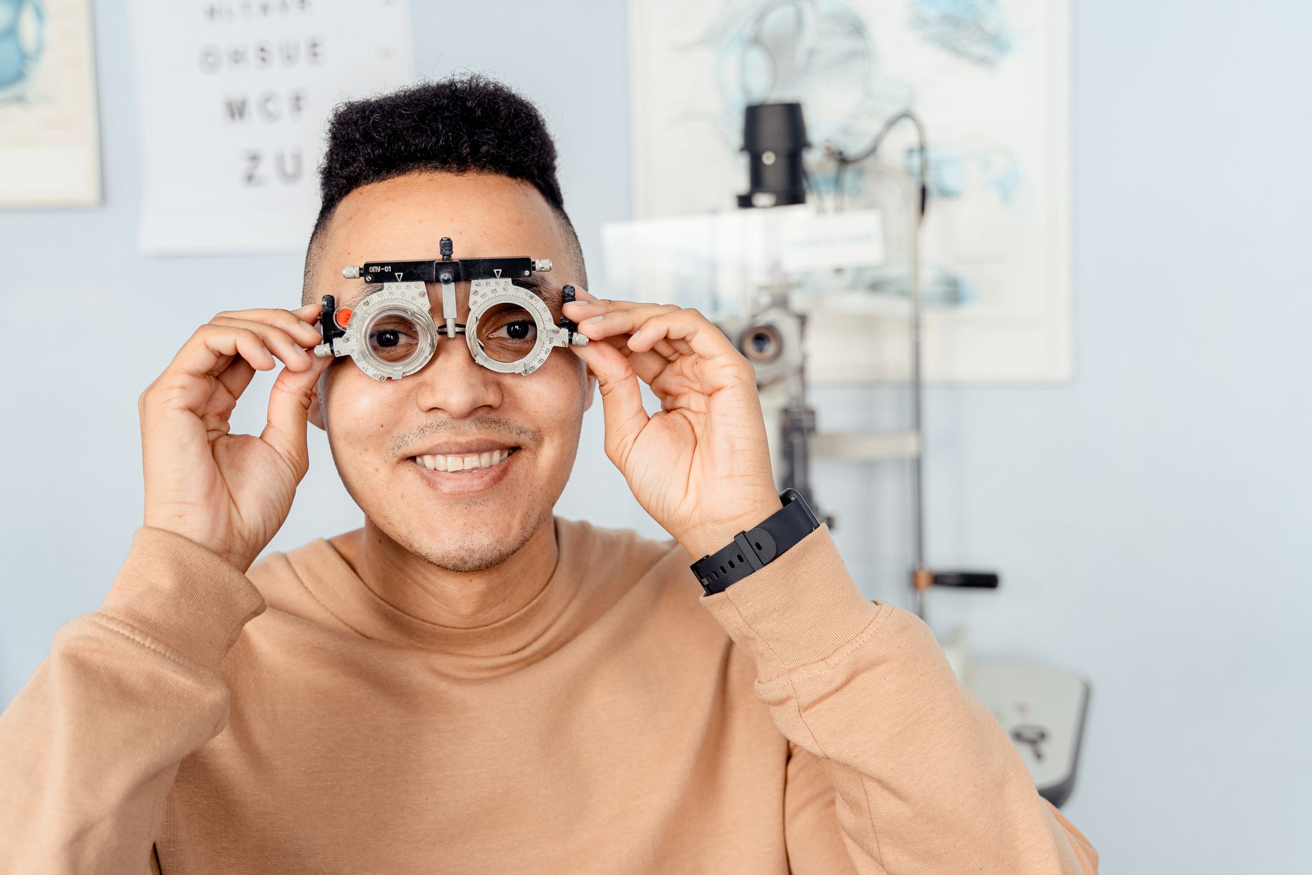 Smiling man holding trial frame in optometry clinic for eye examination.