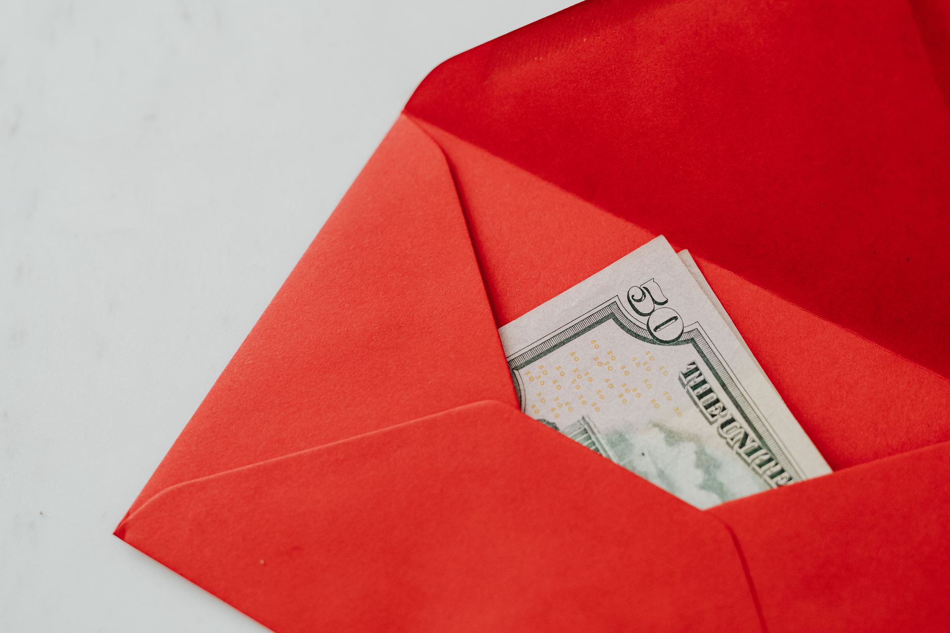 Close-up of fifty dollar bill in a vibrant red envelope, ideal for gift or money exchange stock photo.