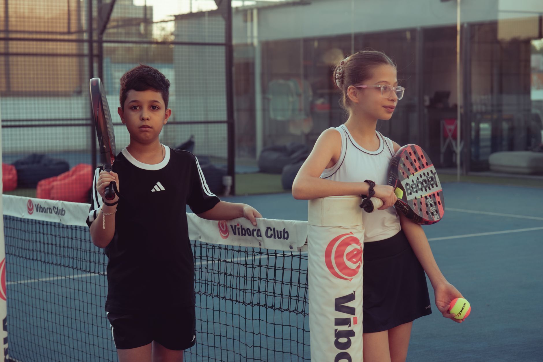 Two kids with paddles and ball on a tennis court at Vibora Club.