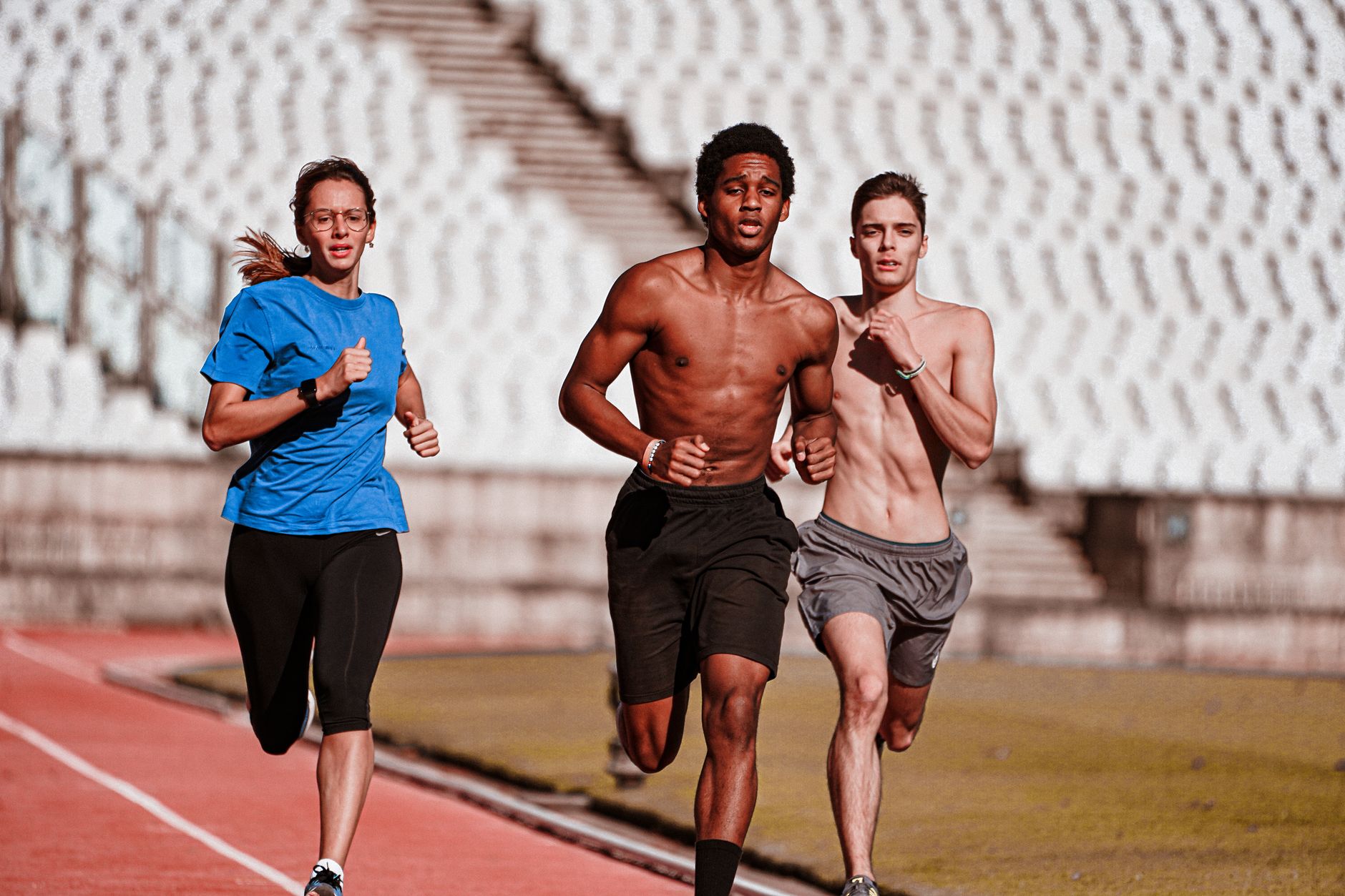 Three athletes competing on an outdoor track, showcasing diversity and determination.