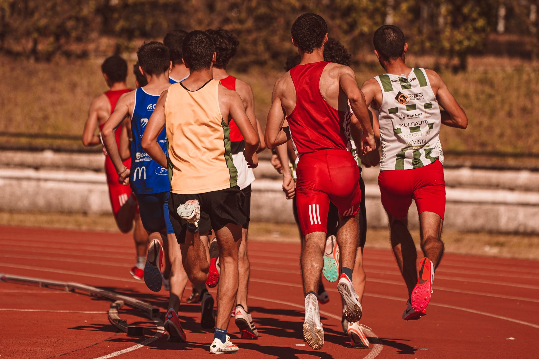 Men competing in a running event on a sunny outdoor track, showcasing athleticism and determination.
