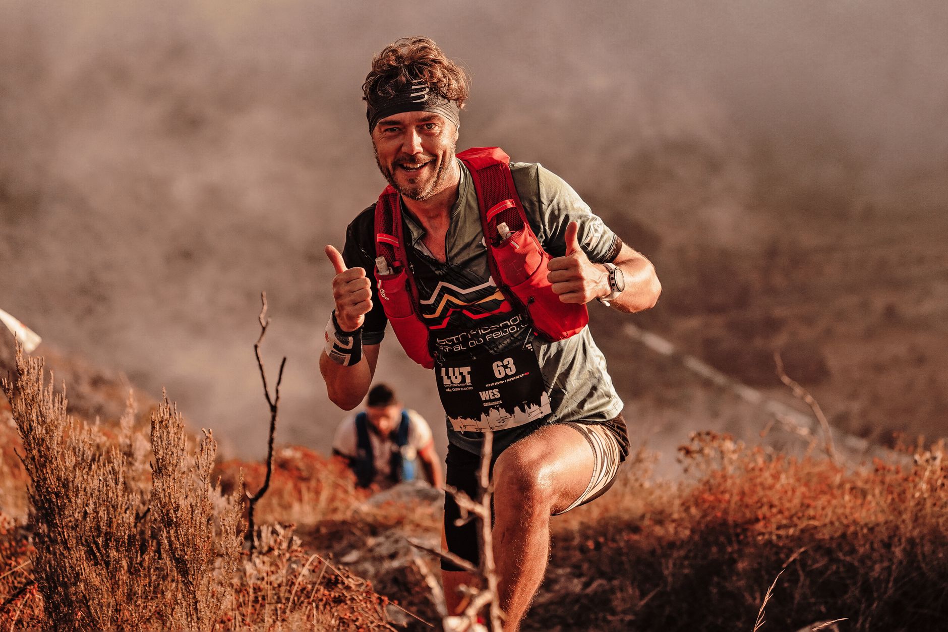 A smiling man in sportswear hiking energetically on a mountain trail showcasing adventure and determination.