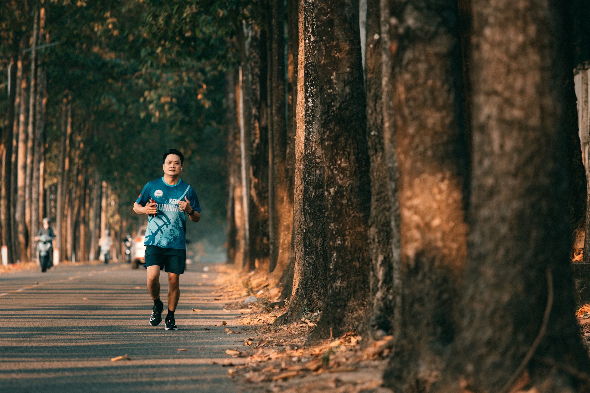 A man jogging along a scenic, tree-lined road, capturing the essence of fitness and nature.