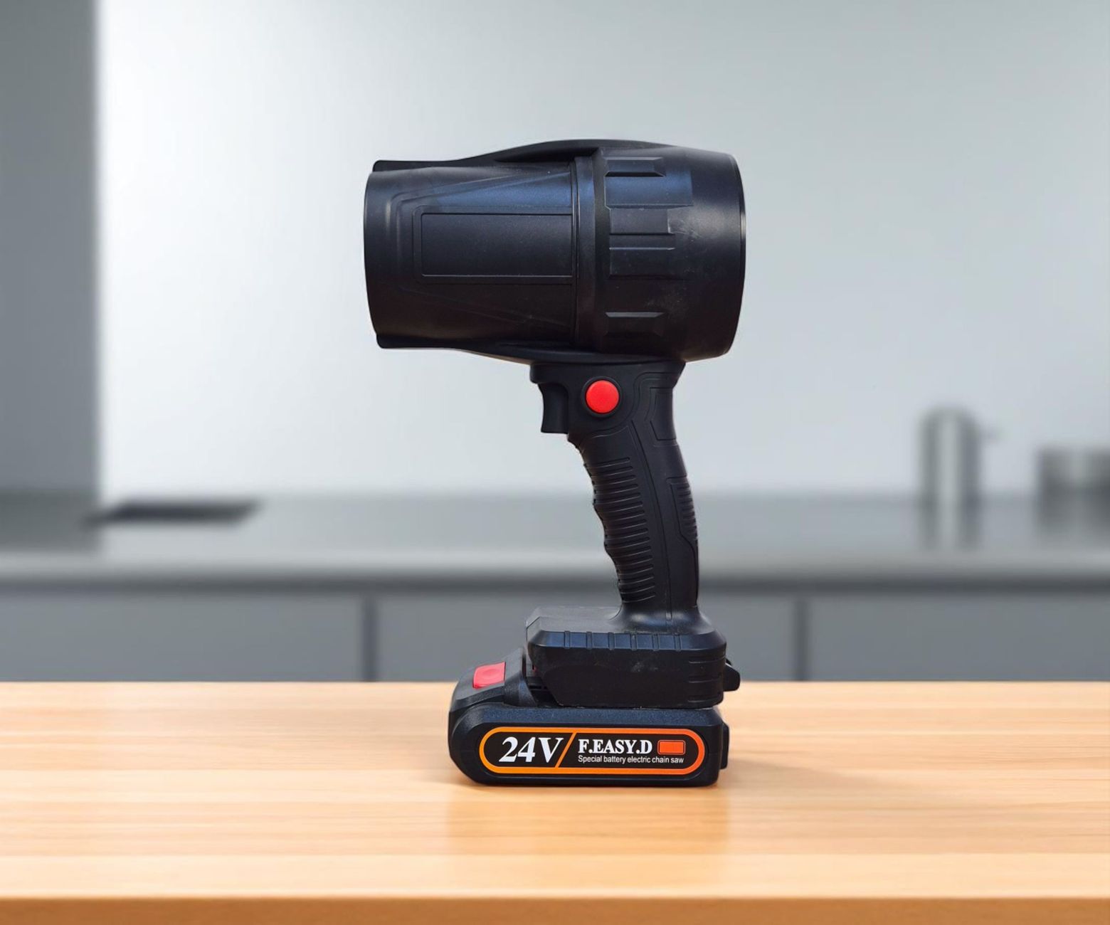 Black 24V cordless spotlight with ergonomic grip on a wooden desk indoors.