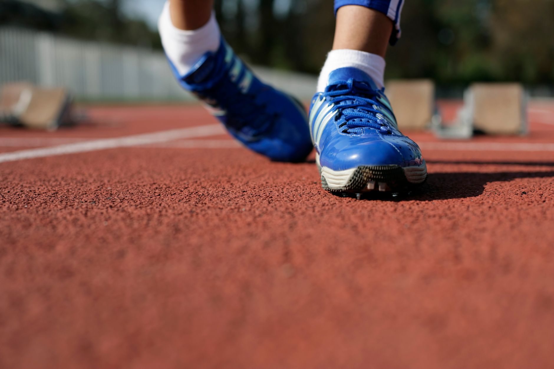 Close-up of a runner's blue shoes on a track, ready to race outdoors.