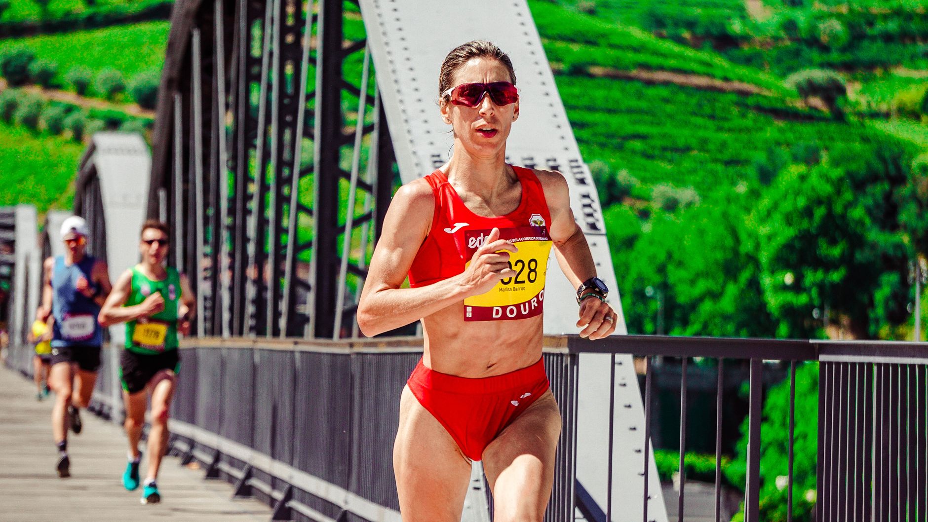 Focused female athlete competing in a marathon on a scenic bridge. Outdoor sports action.