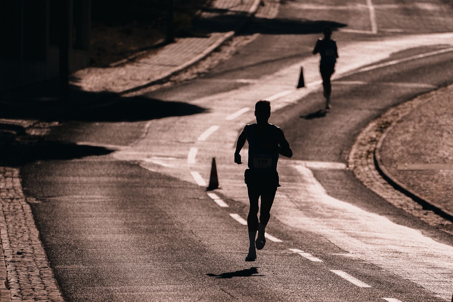 Silhouette of a runner on a street during a race. Captures athletic determination and movement.