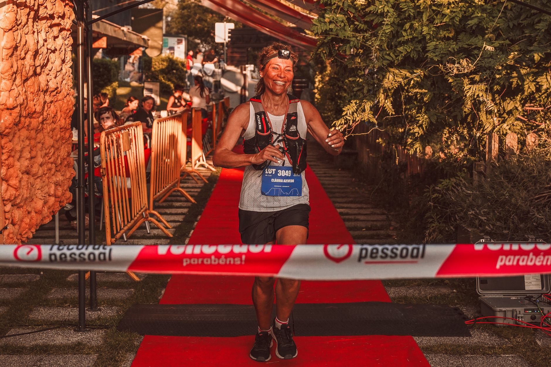 A joyful woman crossing the race finish line triumphantly outdoors.