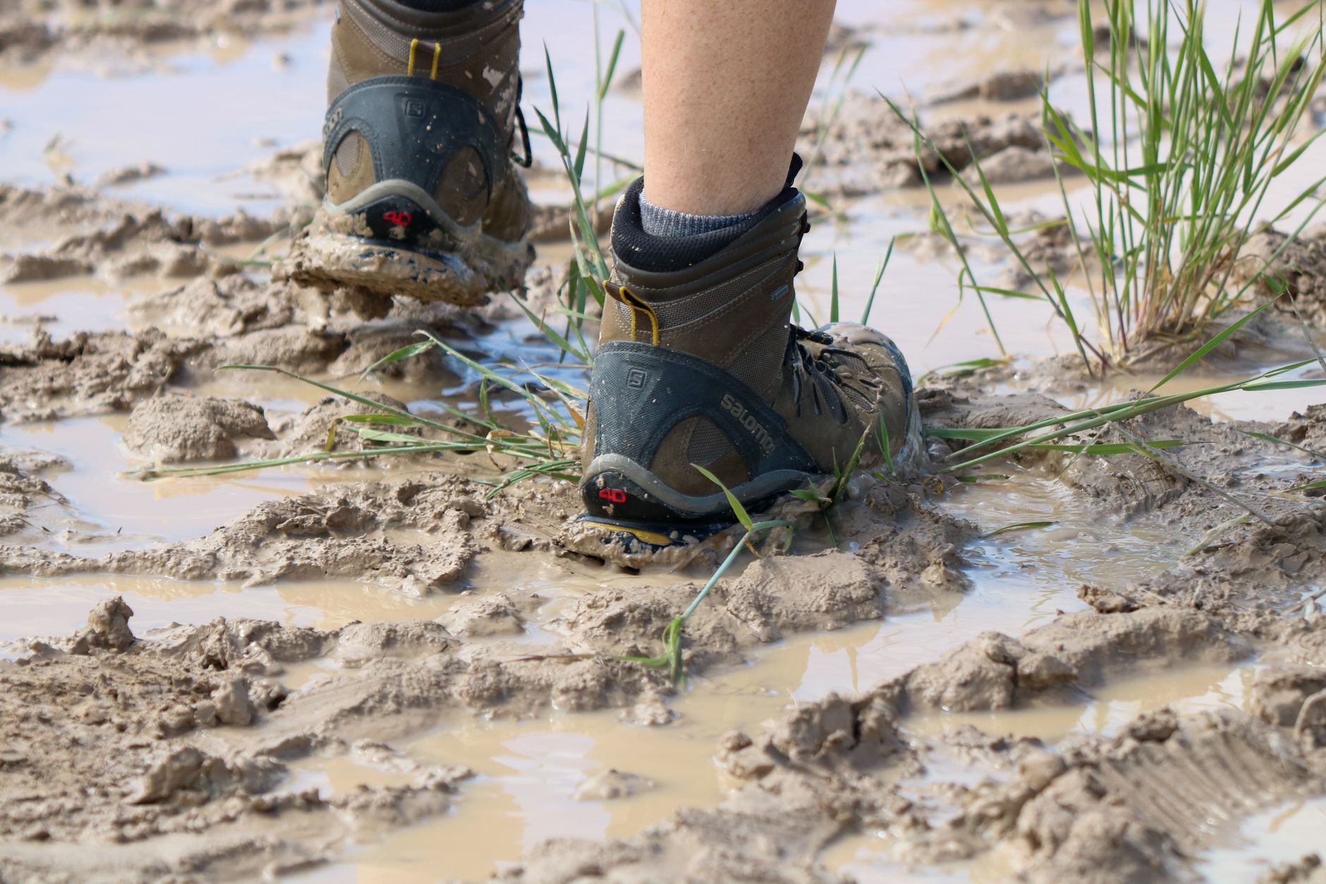 Close-up of hiking boots walking through muddy terrain in South Dakota, capturing adventure and exploration.