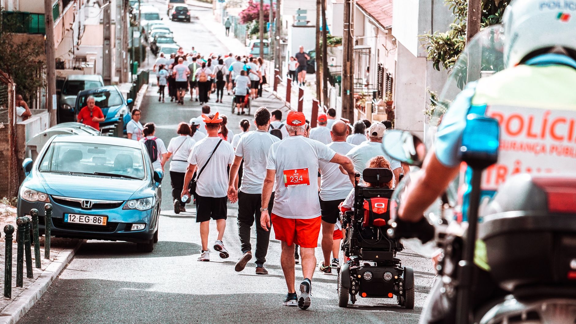 A diverse group of people participating in an urban footrace on a sunny day.