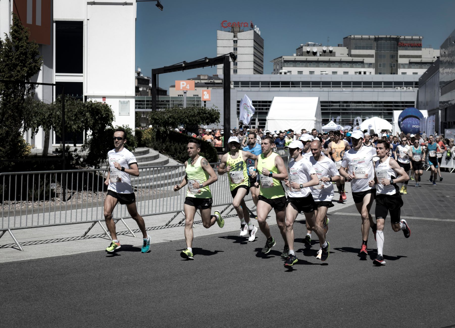 A group of diverse runners competing in an urban marathon on a sunny day.
