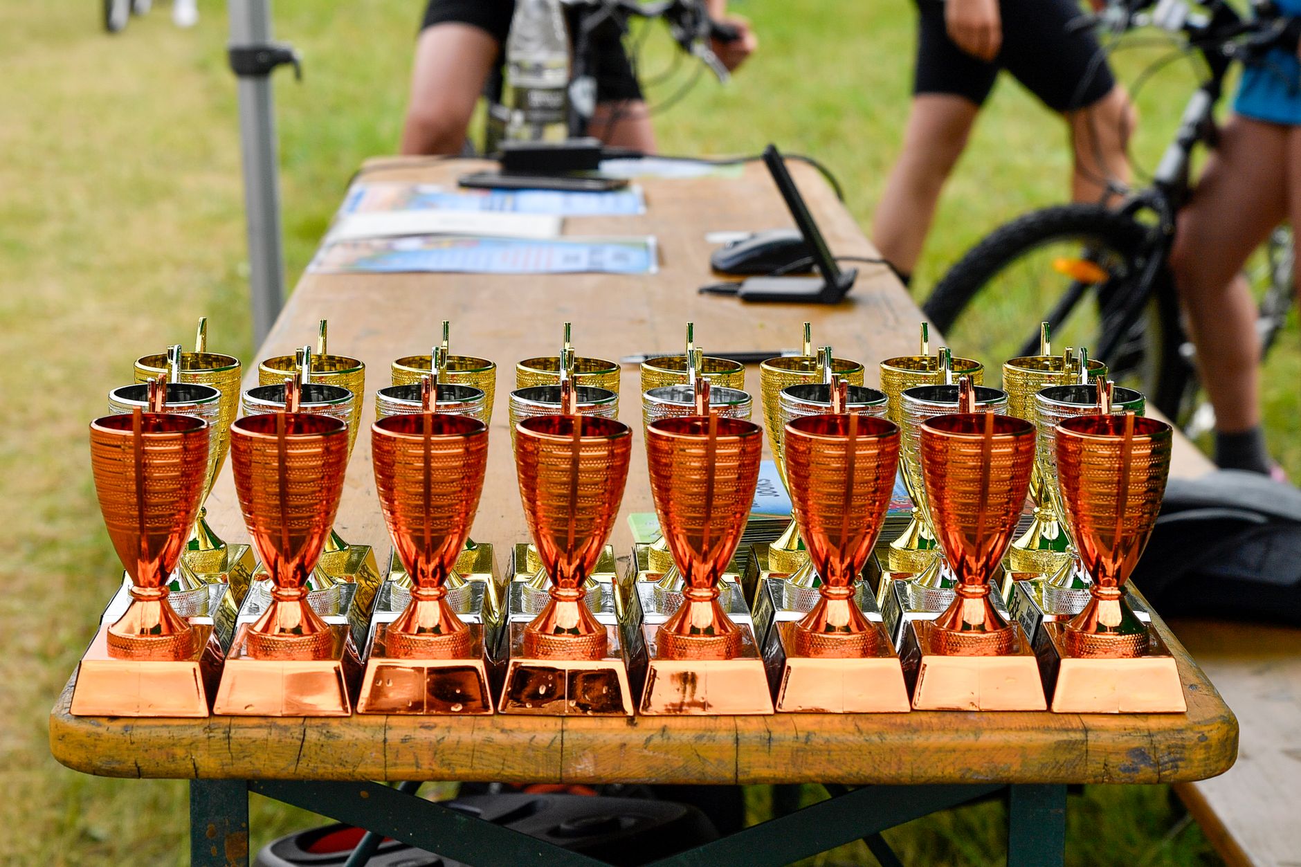 Bronze and gold trophies displayed on a wooden table at an outdoor cycling event in Estonia.