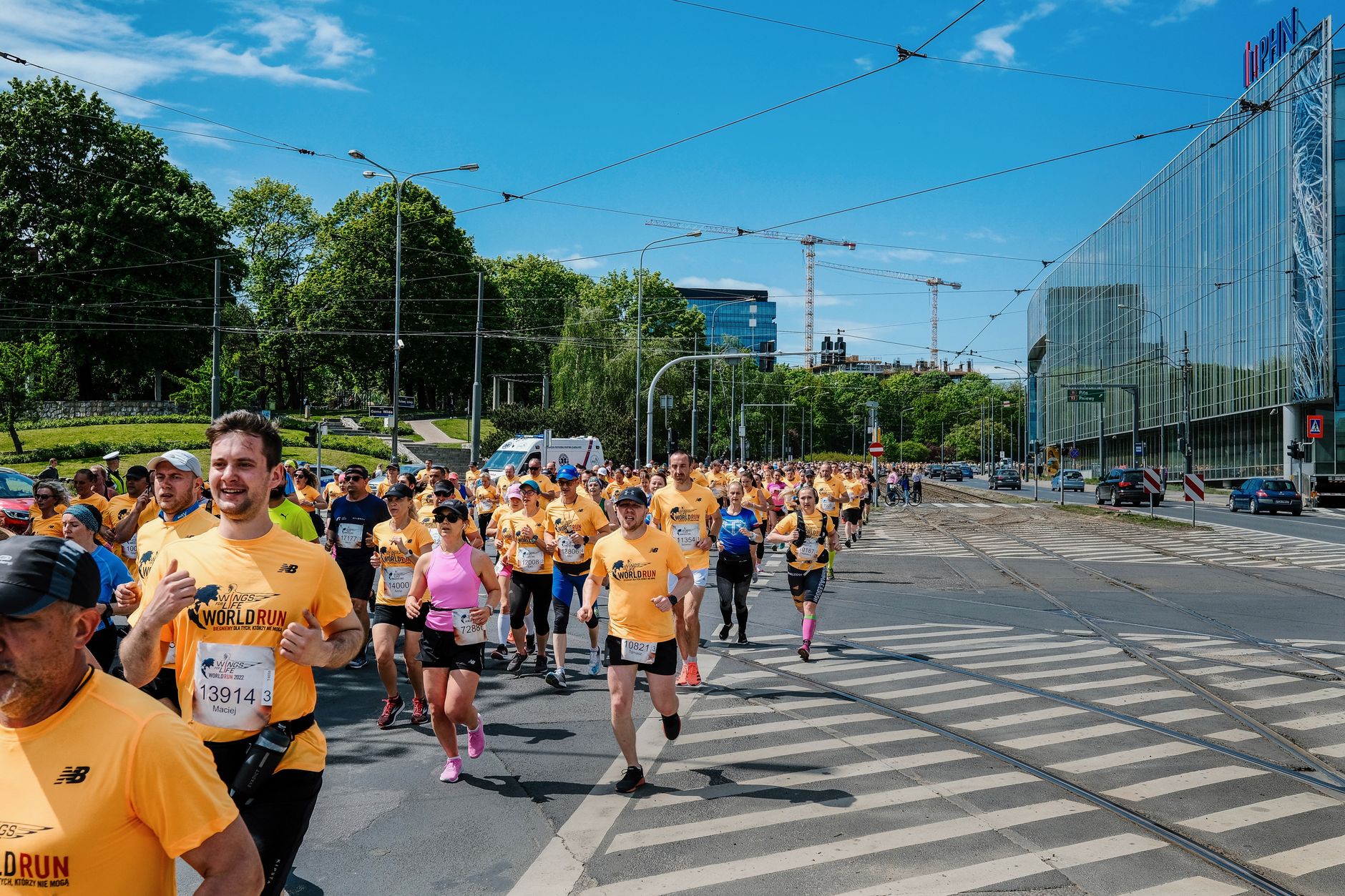 Large group of diverse runners participating in a city race in Poznań, Poland on a sunny day.