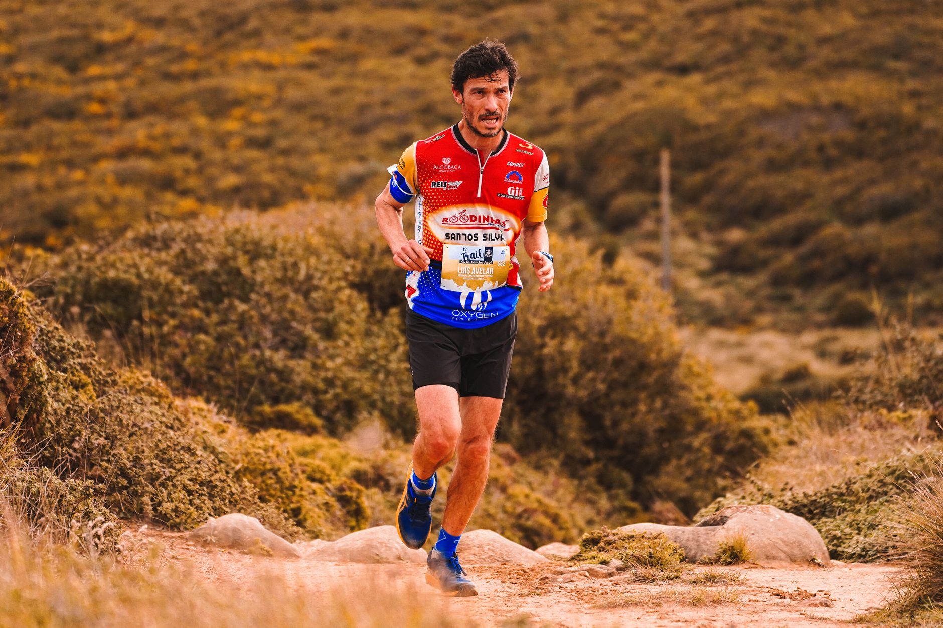 Focused athlete running through rugged terrain during a trail race.