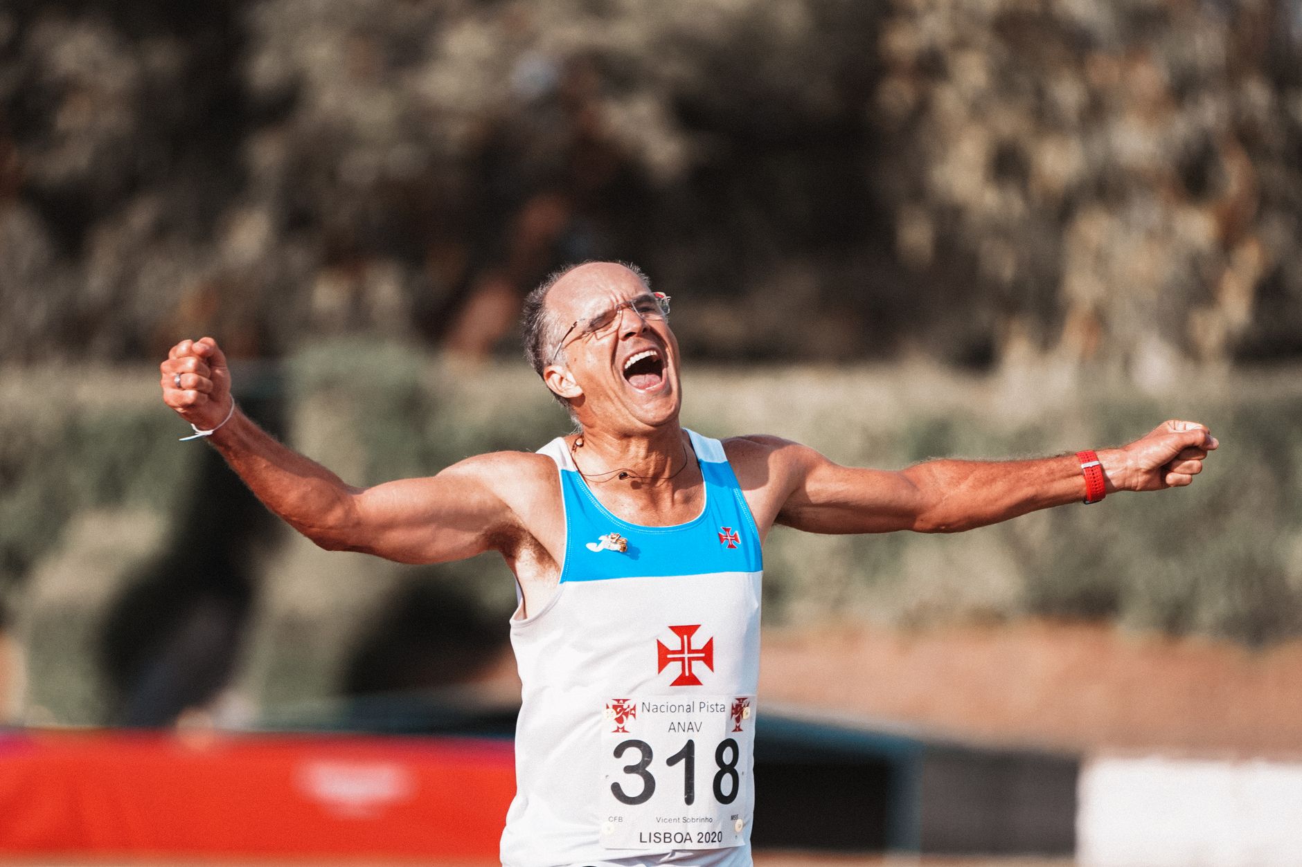 Glad senior male runner with arms outstretched and mouth opened rejoicing success in running competition