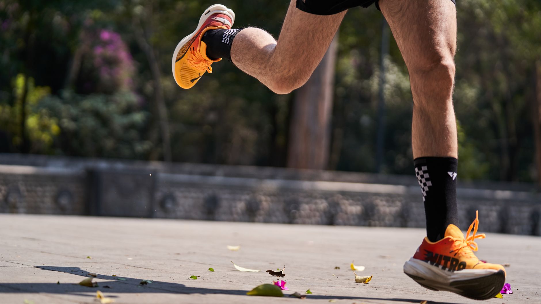 Dynamic shot of a runner in vibrant orange sneakers, capturing movement and energy in an outdoor setting.