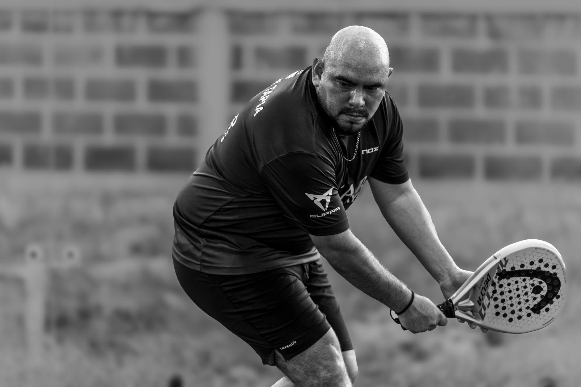 A focused player in an intense padel game outdoors in Mérida, Yucatán. Captured in grayscale for dramatic effect.