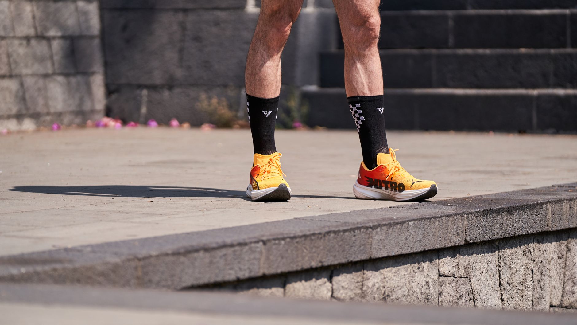 Close-up shot of a runner's legs wearing bright orange shoes and black socks.