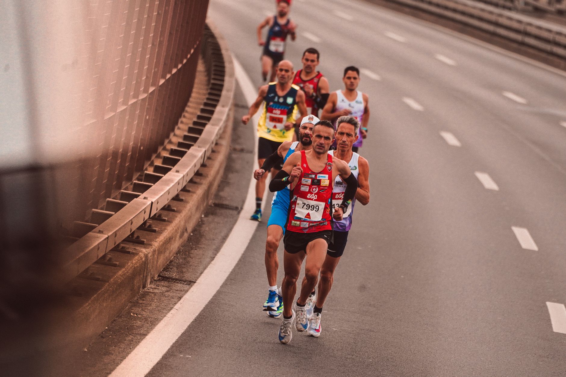 A group of male athletes competing in a city marathon, featuring diverse runners and dynamic movement.