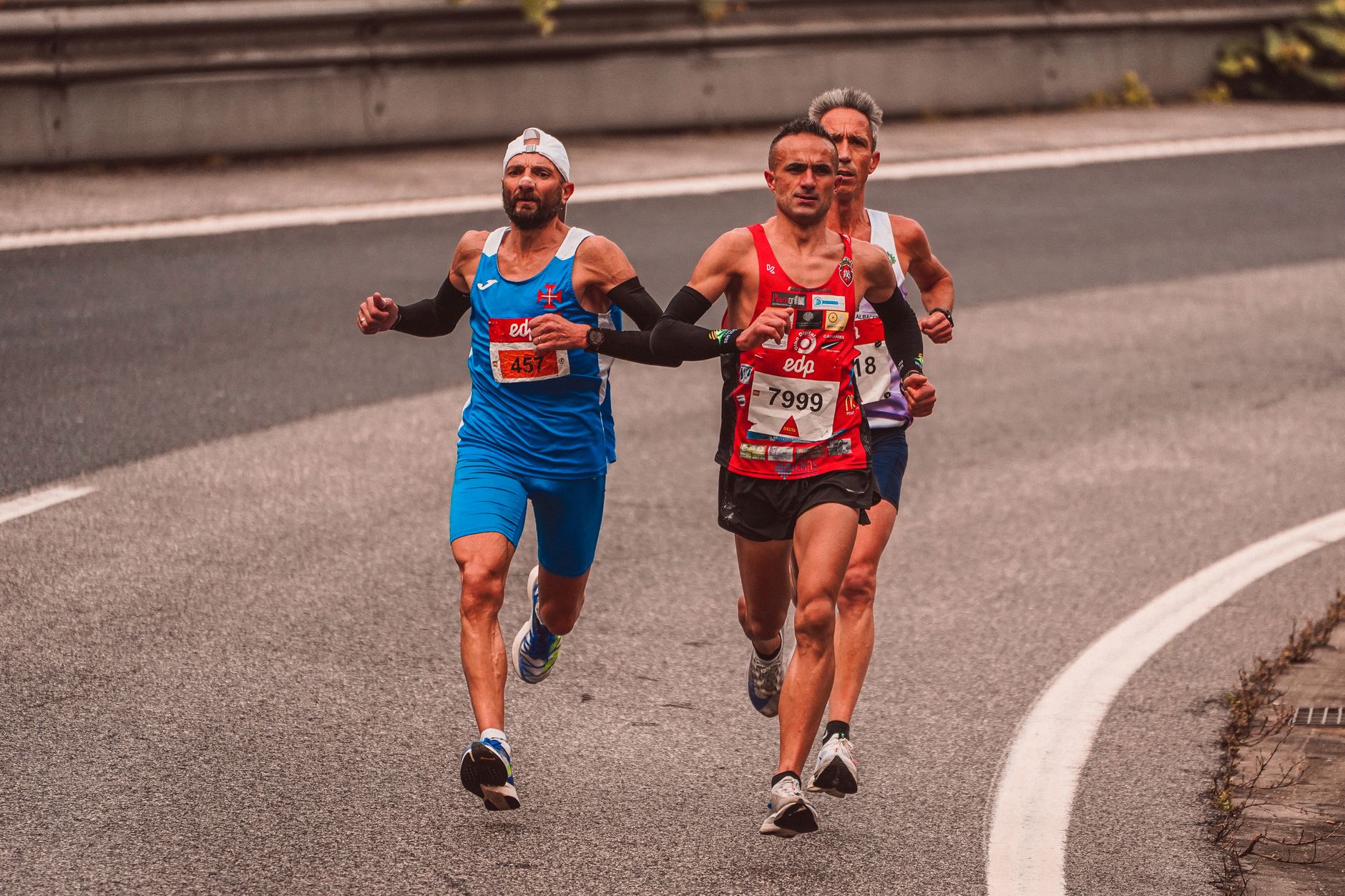 Three male runners competing in a marathon on a city road. Capturing endurance and athleticism.