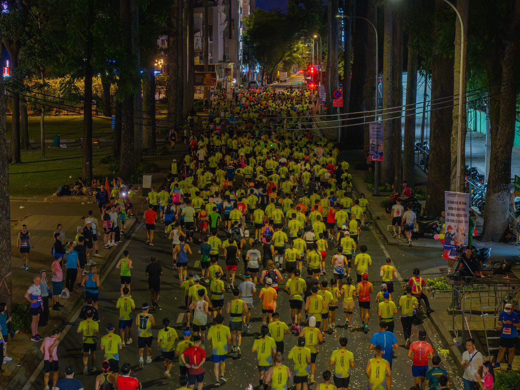 A large group of runners participate in a nighttime urban marathon event.