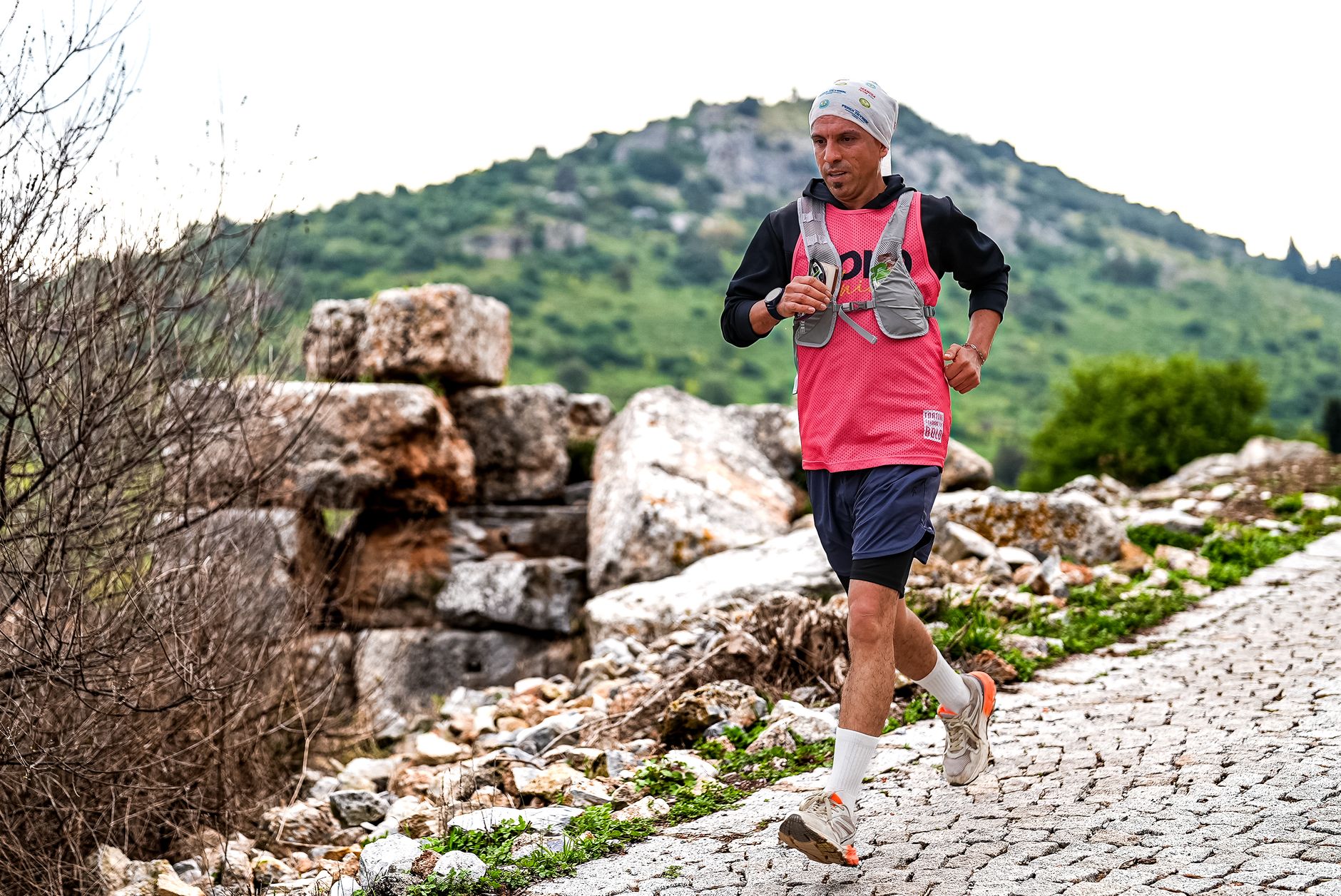 Athlete running on rocky terrain in İzmir, showcasing determination and endurance with scenic mountain backdrop.