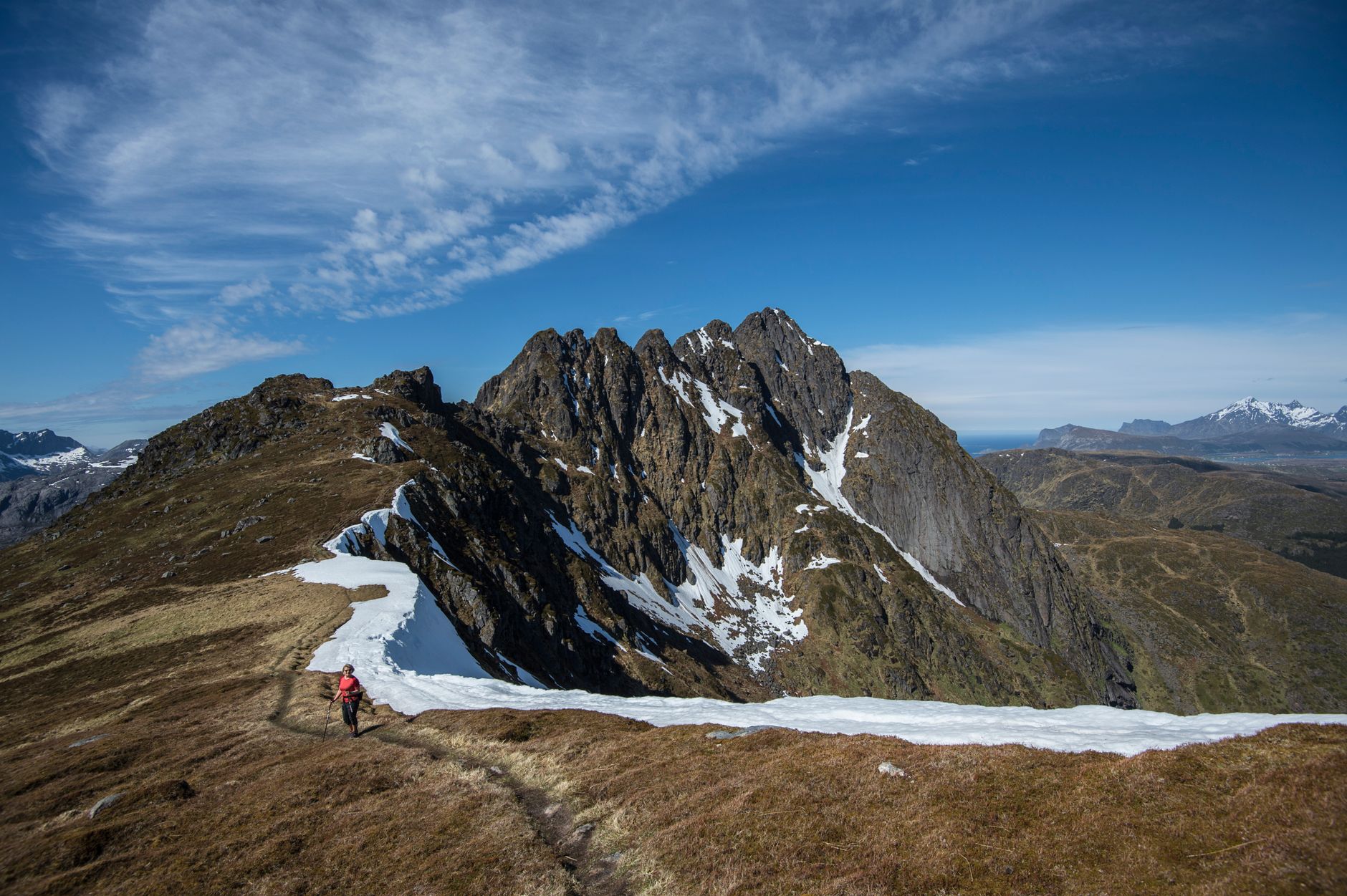 A lone hiker traverses the breathtaking Lofoten mountains in Nordland, Norway.