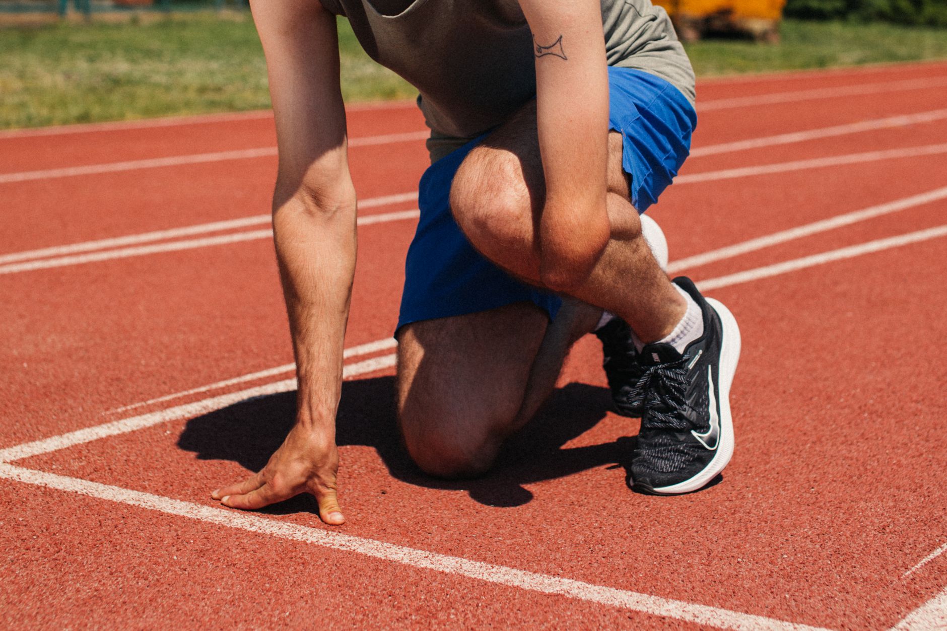 Determined athlete at starting line of outdoor track, ready to race with focus and strength.