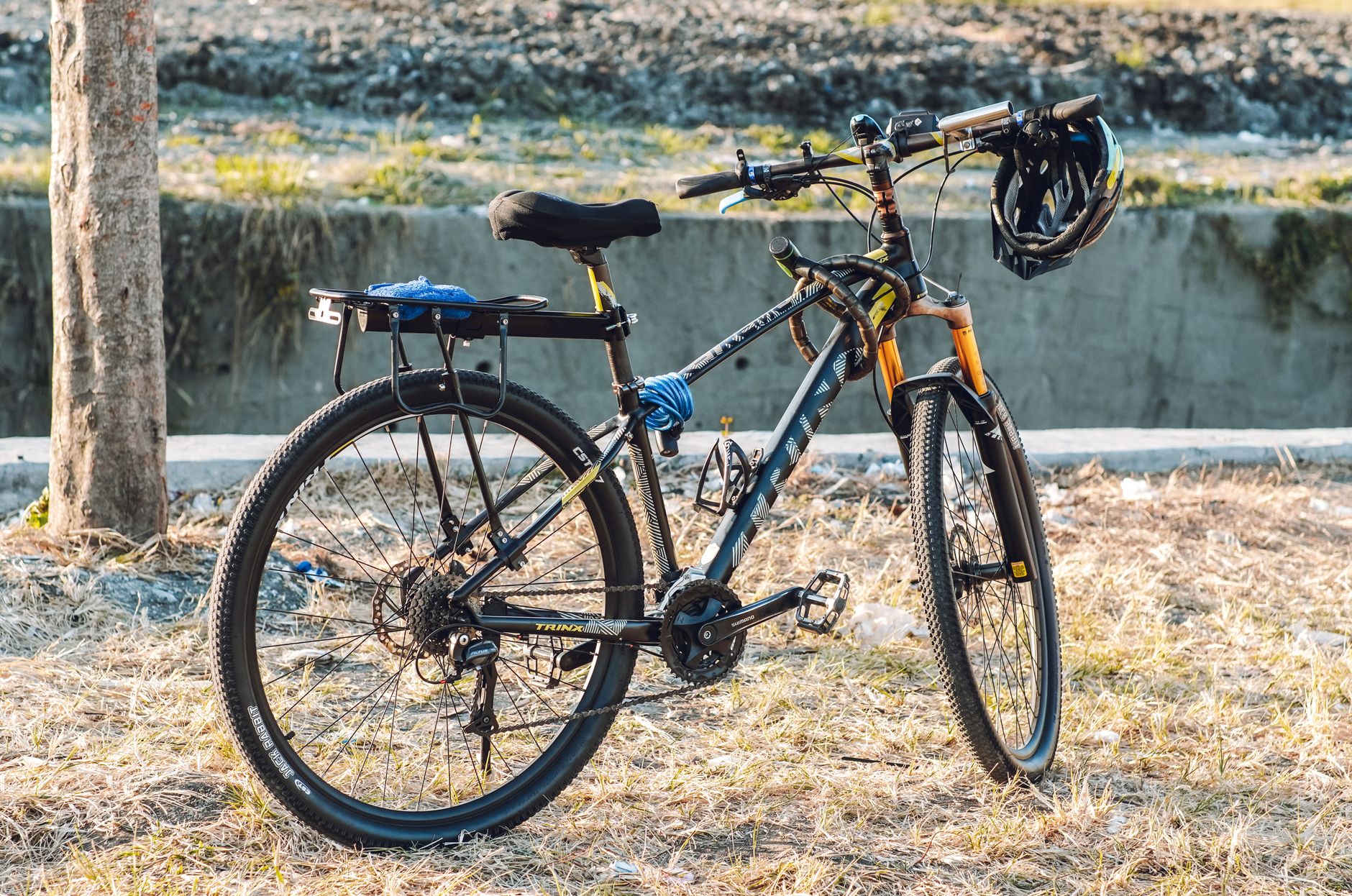 A mountain bike parked outdoors with a helmet hanging on the handlebar.