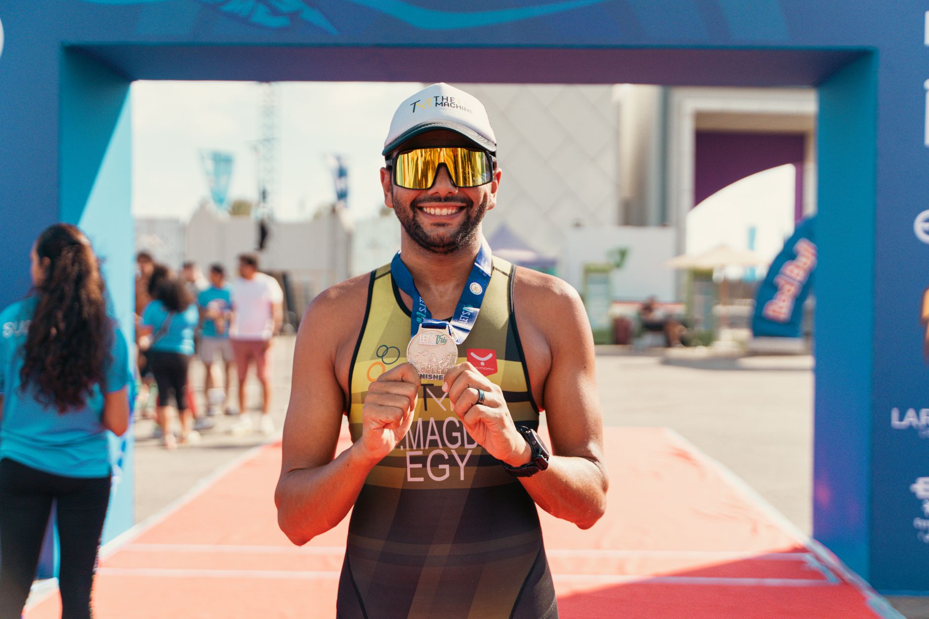 A joyful triathlete proudly displays his medal after a successful race finish outdoors.
