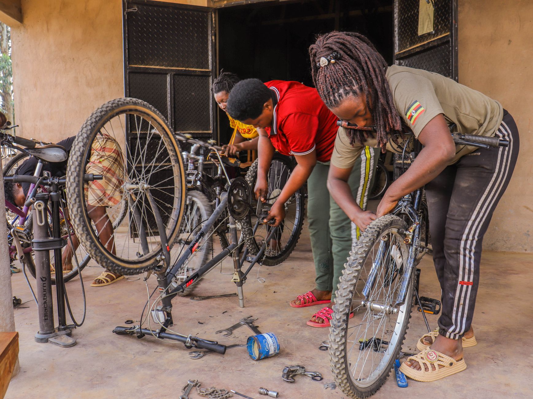 Three women collaboratively repairing bicycles in an indoor workshop.