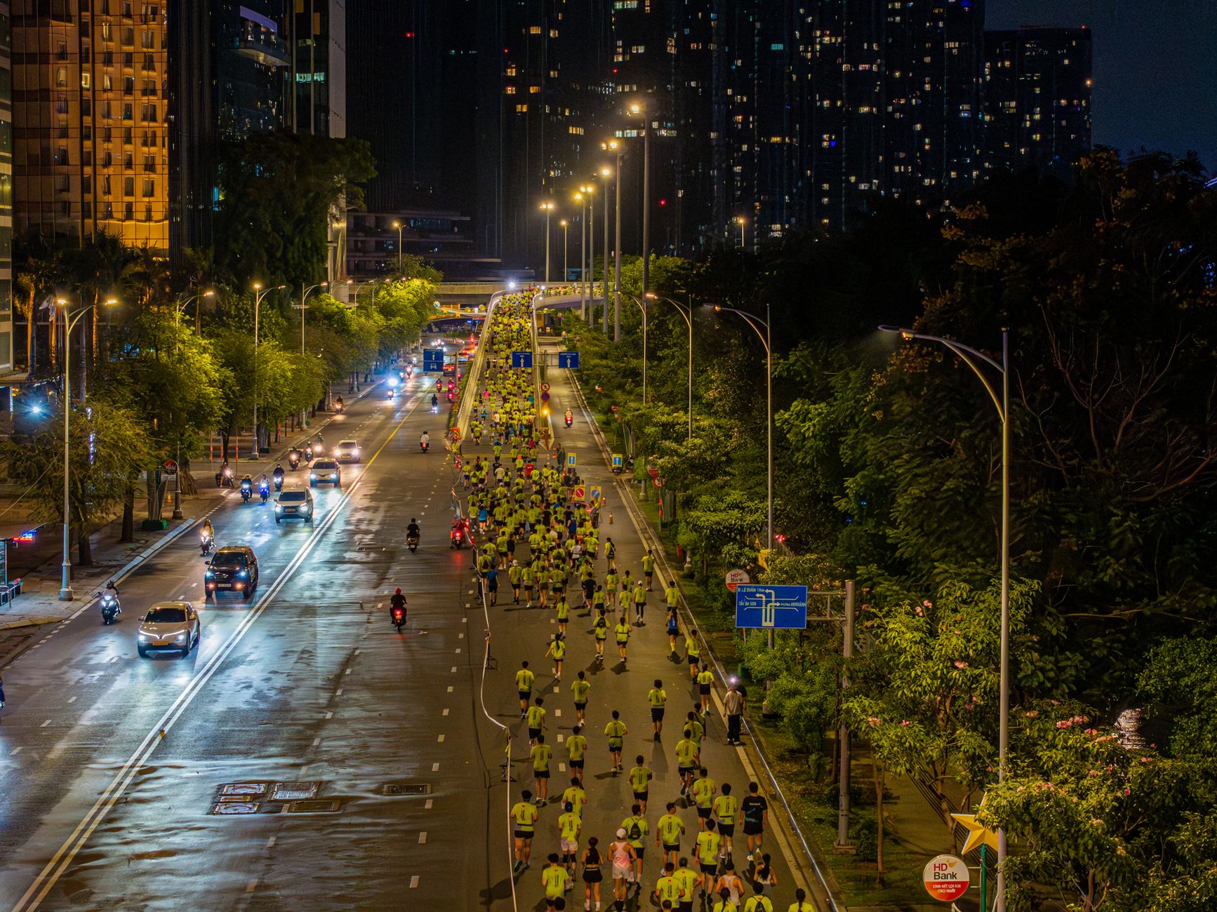 City marathon at night with athletes running under streetlights on a closed road.
