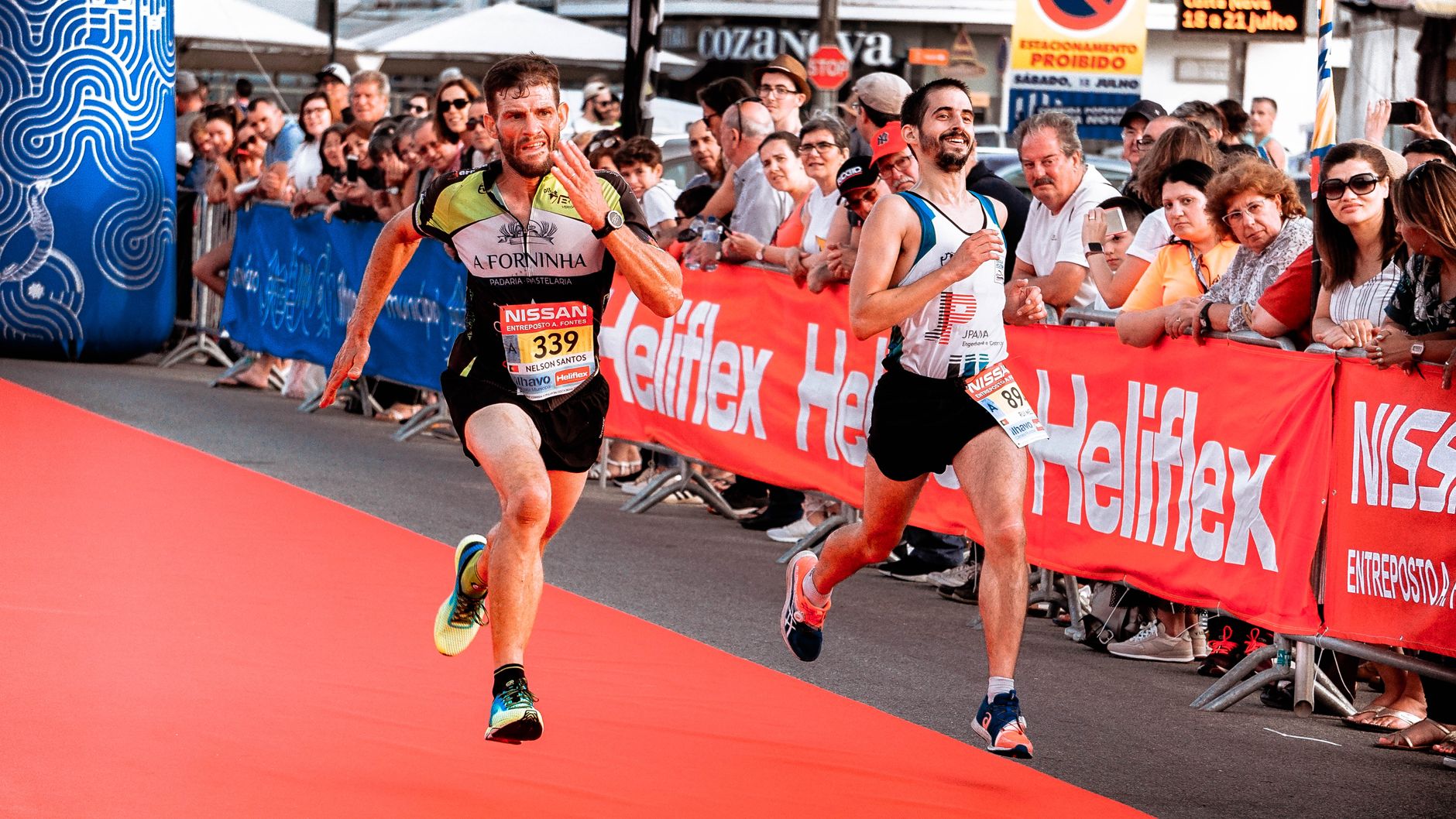 Two marathon runners sprint towards the finish line amid a cheering crowd during a race.