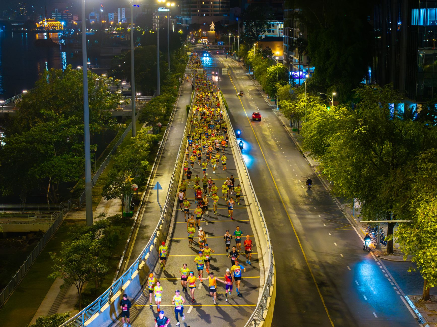 Aerial view of marathon runners on a city street at night, bright lights and energy.