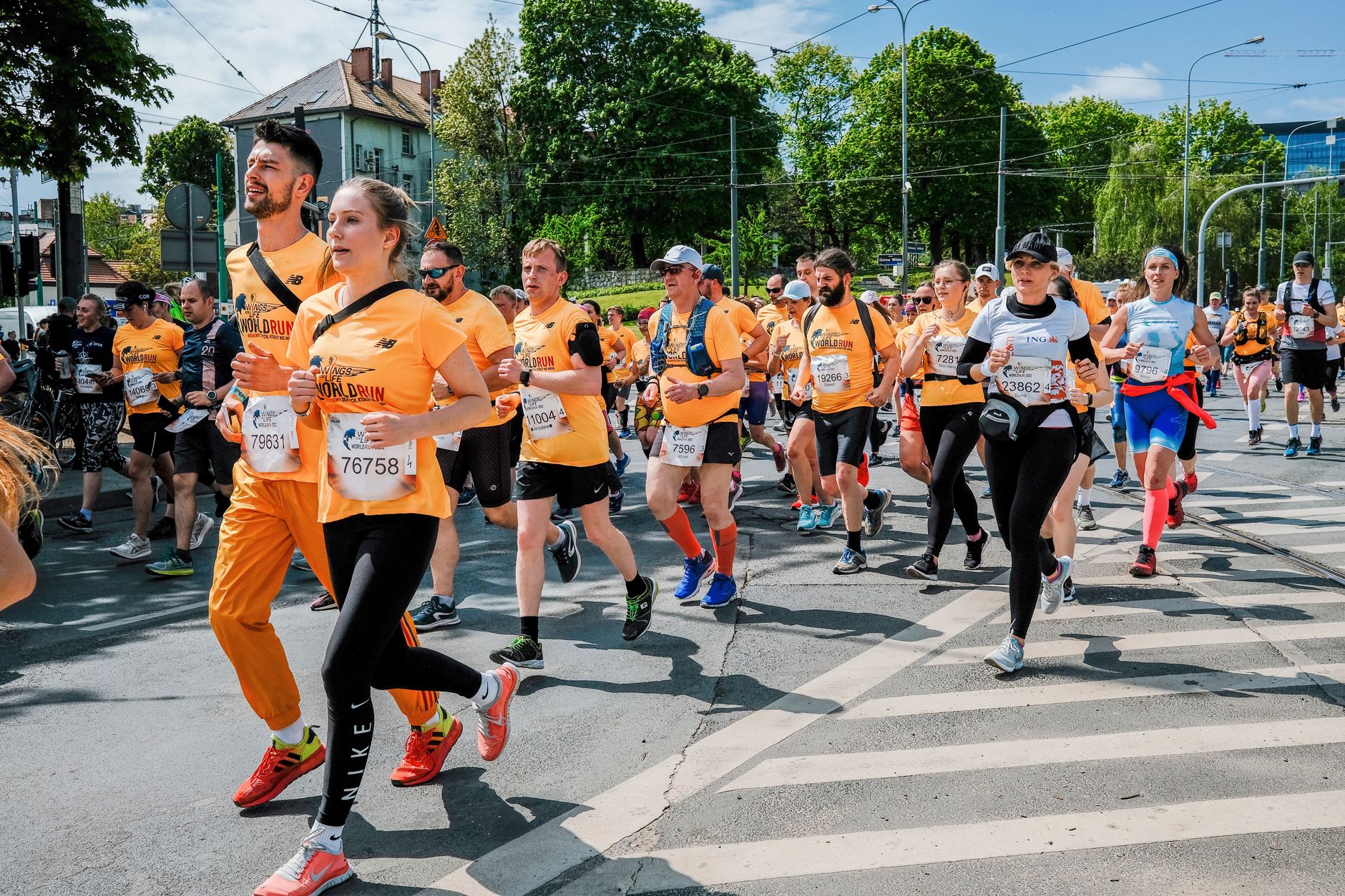 A diverse group of runners competing in a sunny marathon event in Poznań, Poland.