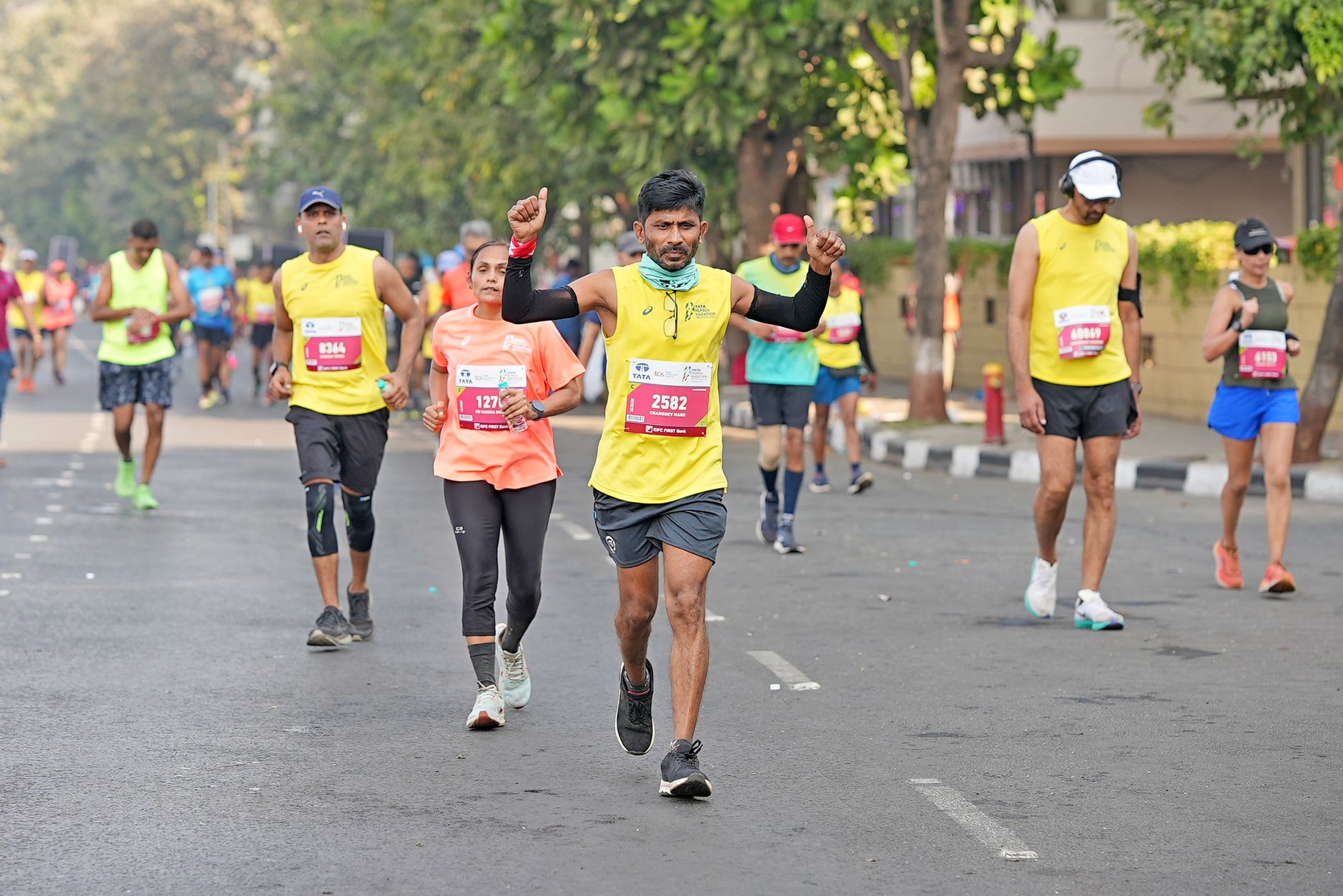Several runners, both men and women, participating in a city marathon on a sunny day.