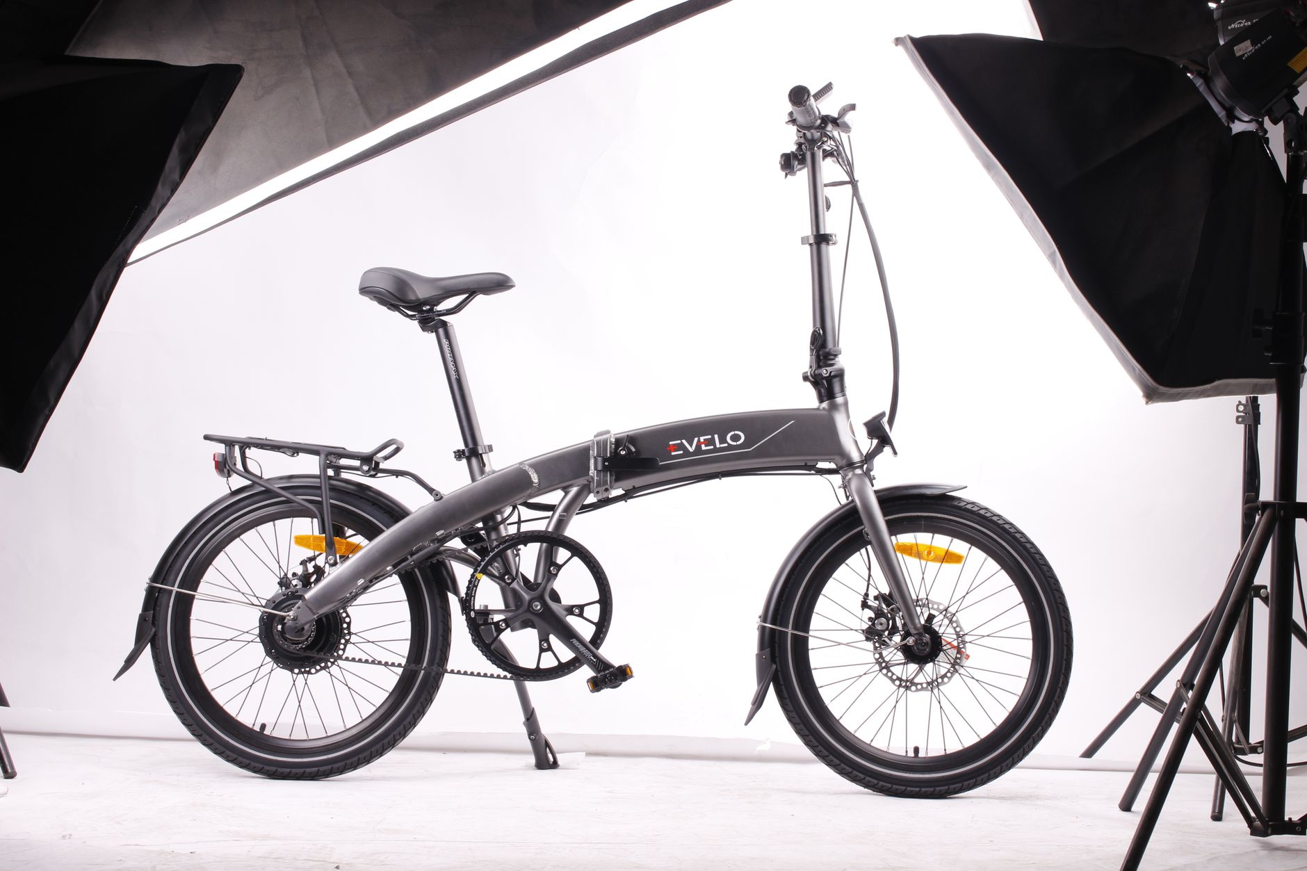 Modern foldable black electric bicycle displayed in a studio environment with white background and lighting equipment.