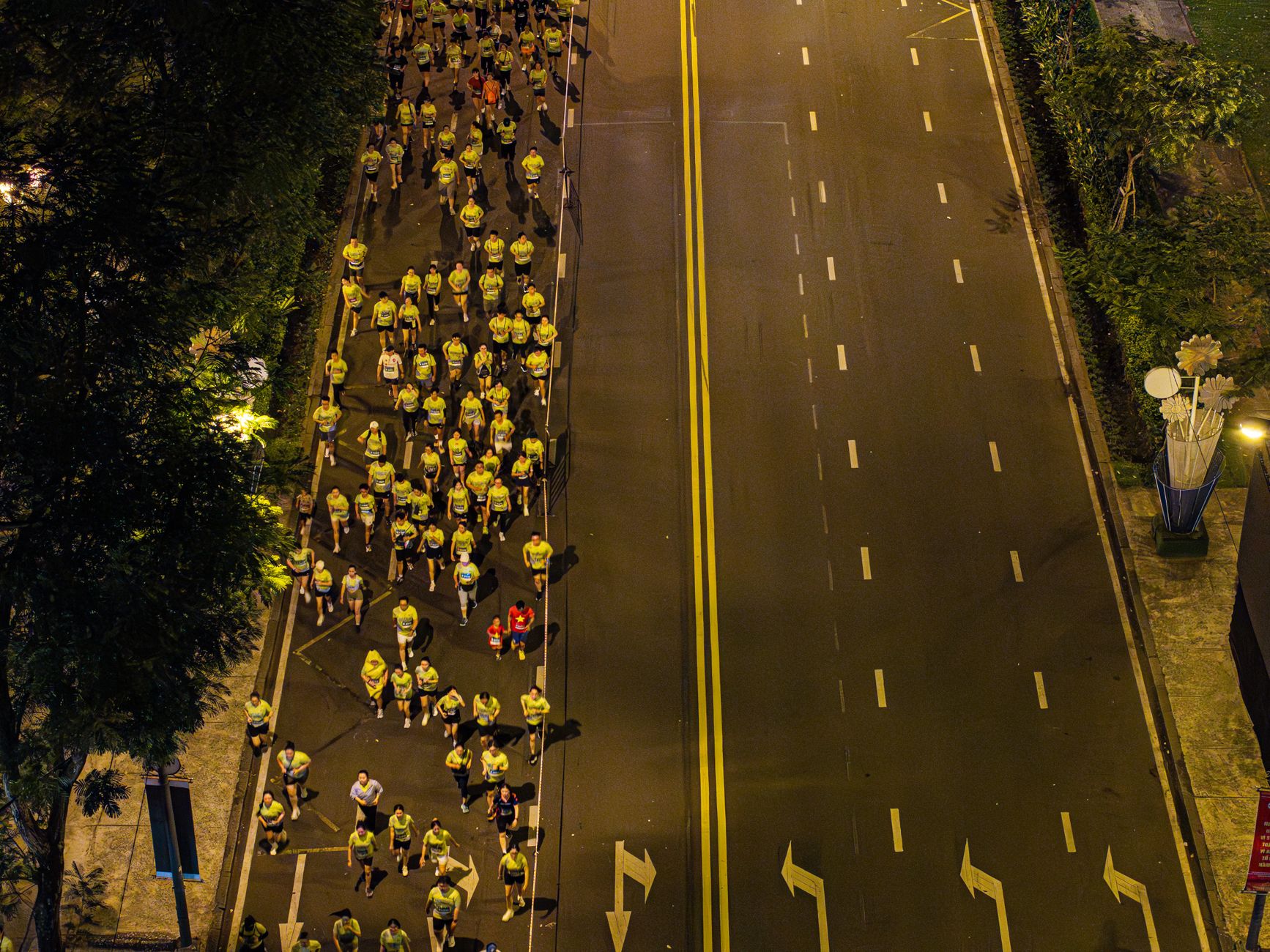 Aerial view of runners participating in a nighttime marathon on a city street.