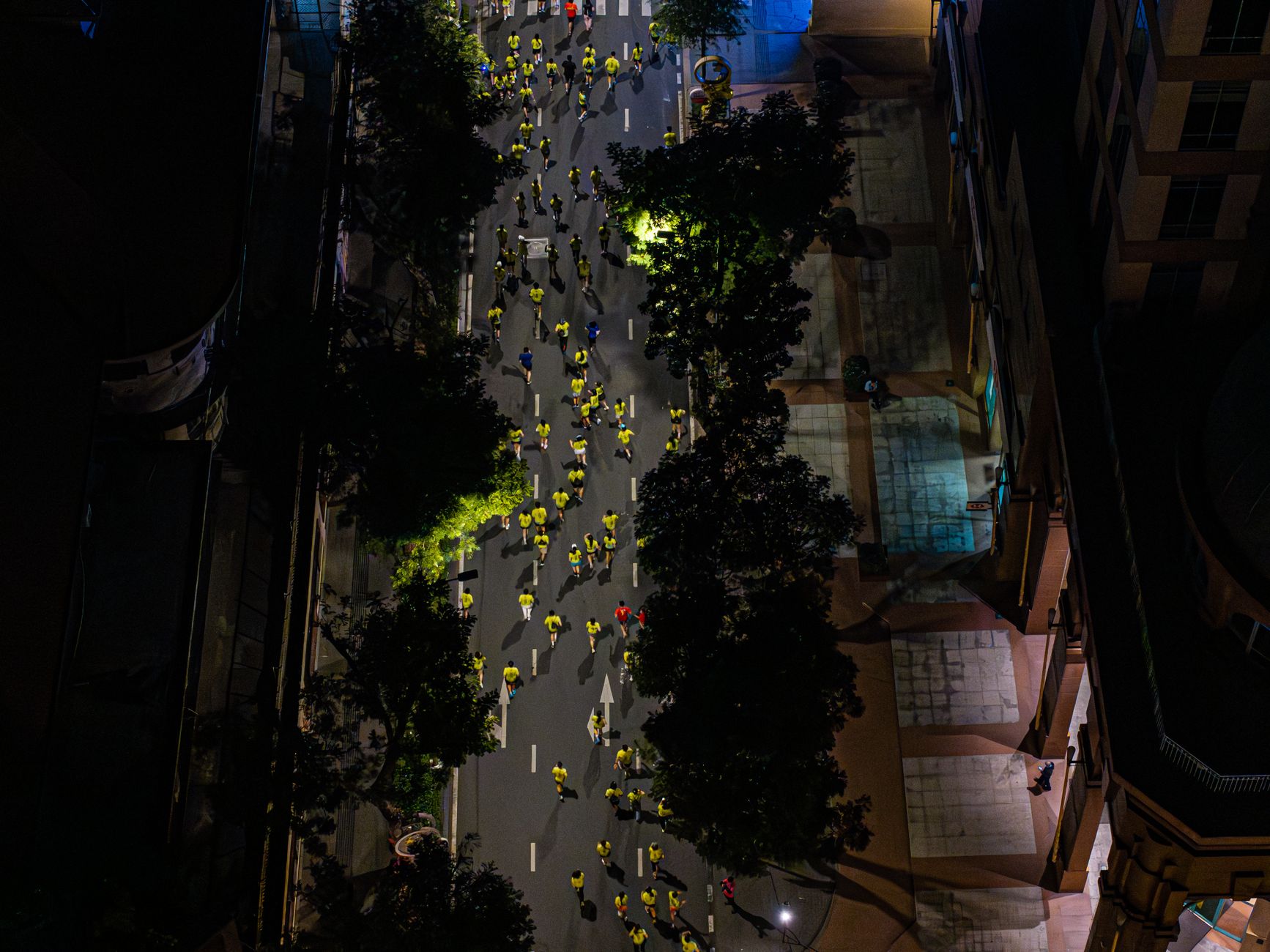 Aerial shot of a nighttime city marathon with runners.