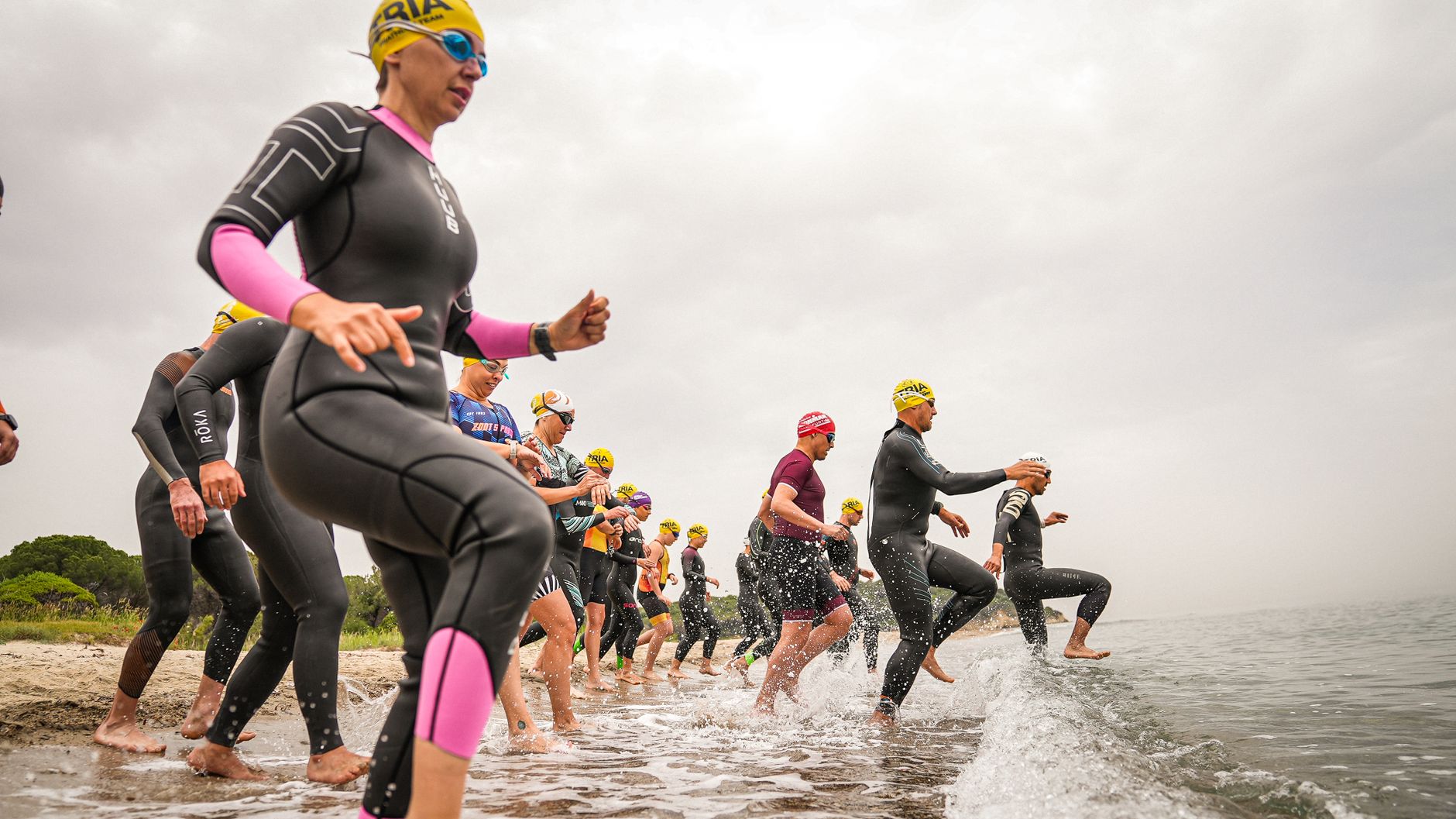 Triathletes in wetsuits begin their race on a beach in Gelibolu, Turkey.