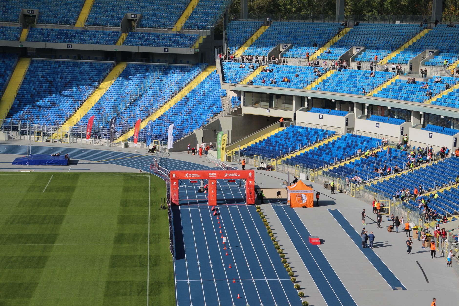 Aerial view of a vibrant stadium with blue seating and a running track filled with spectators.