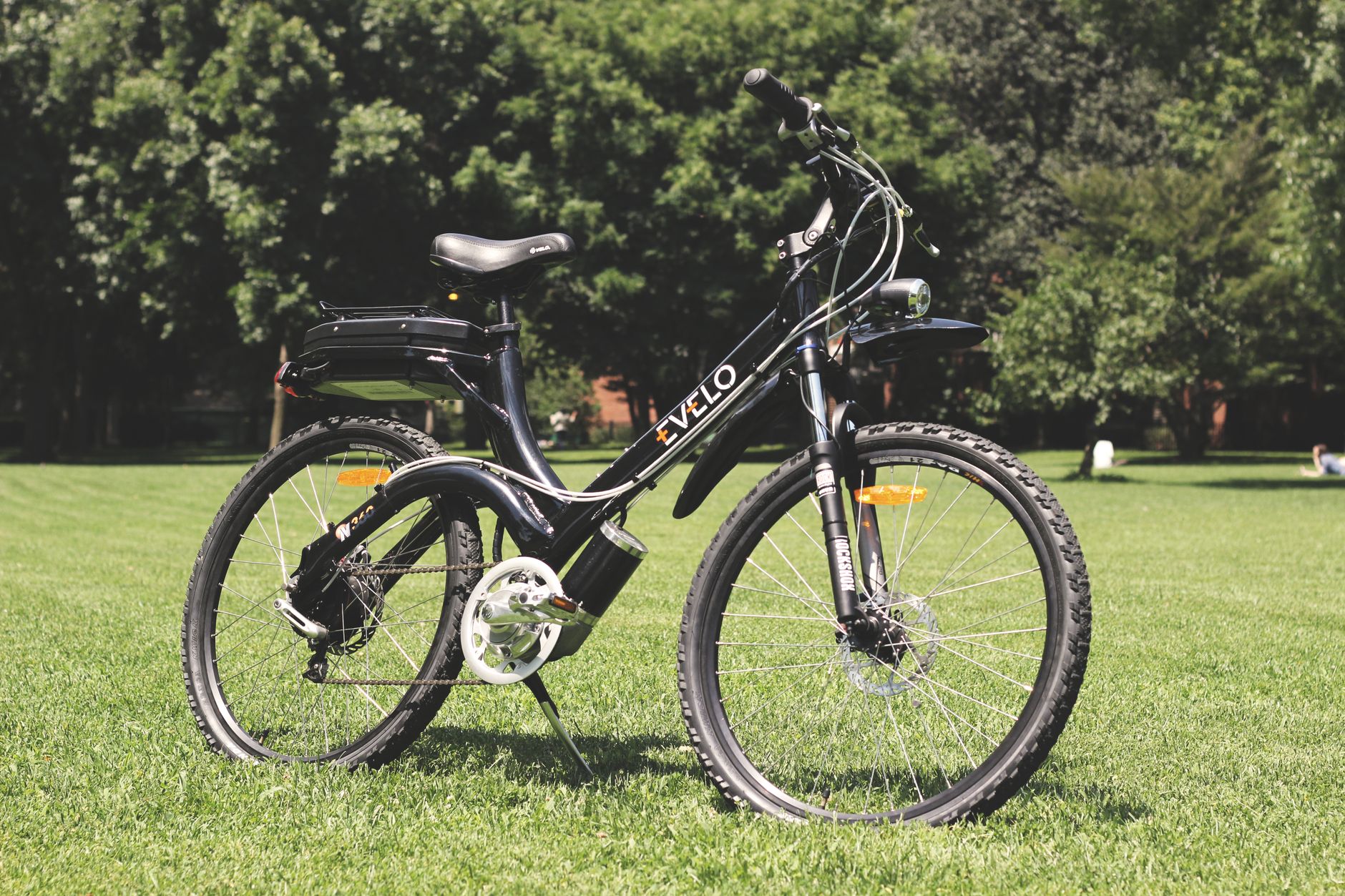 A stylish electric bike parked on lush green grass under the sunny sky.