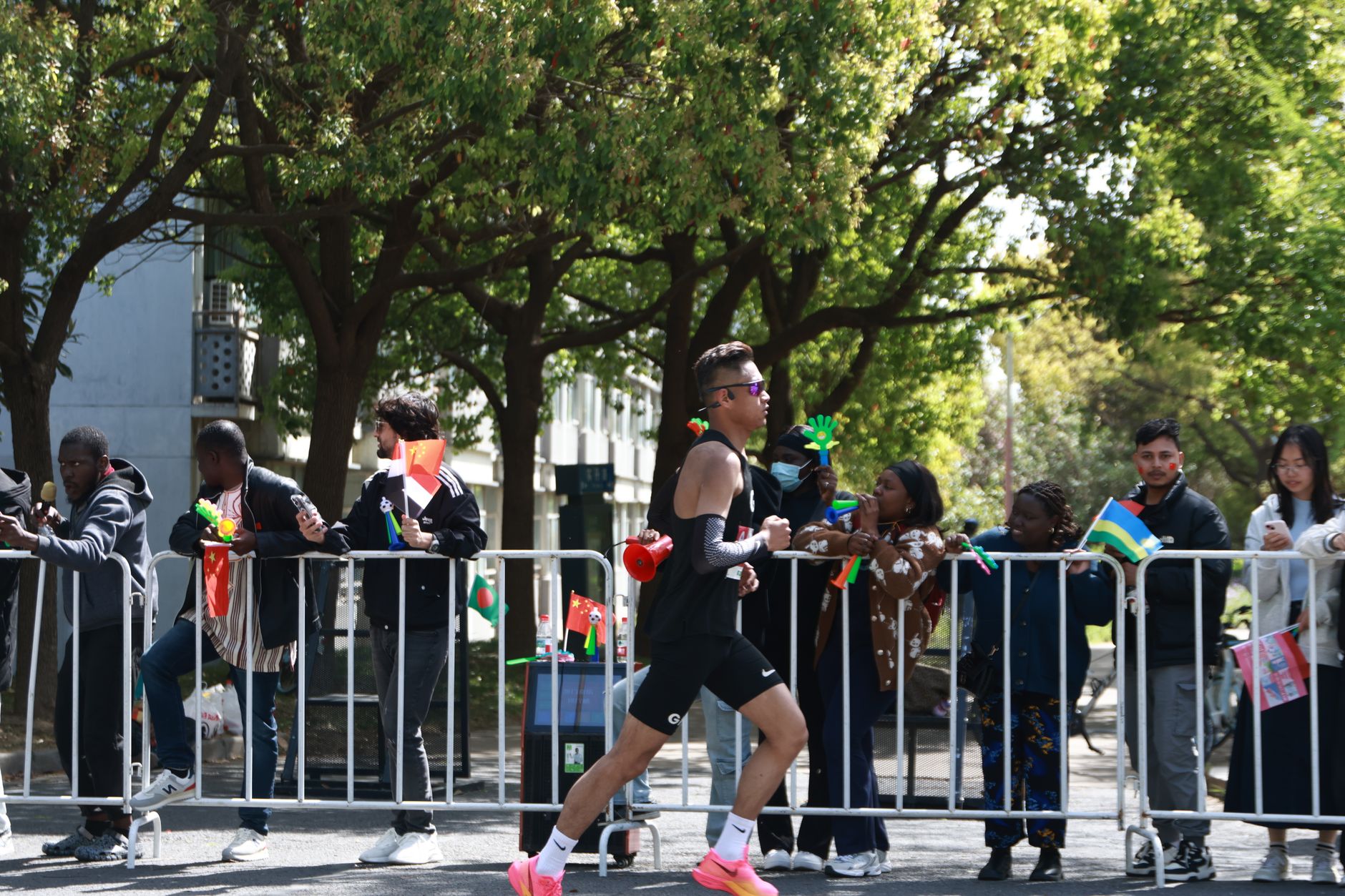 Runner in black racing past cheering crowd at outdoor marathon event.
