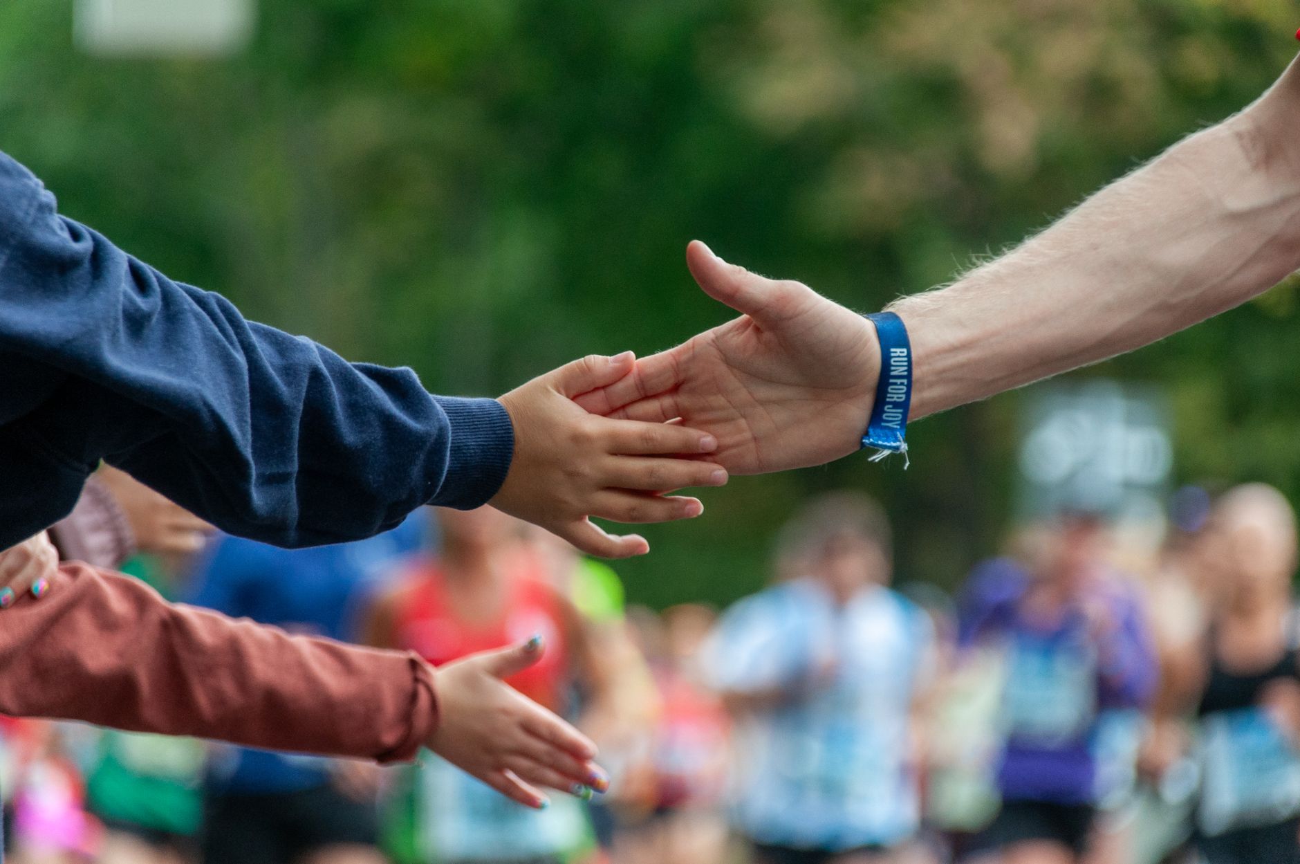 A runner high-fives a spectator during an outdoor marathon, symbolizing support and encouragement.