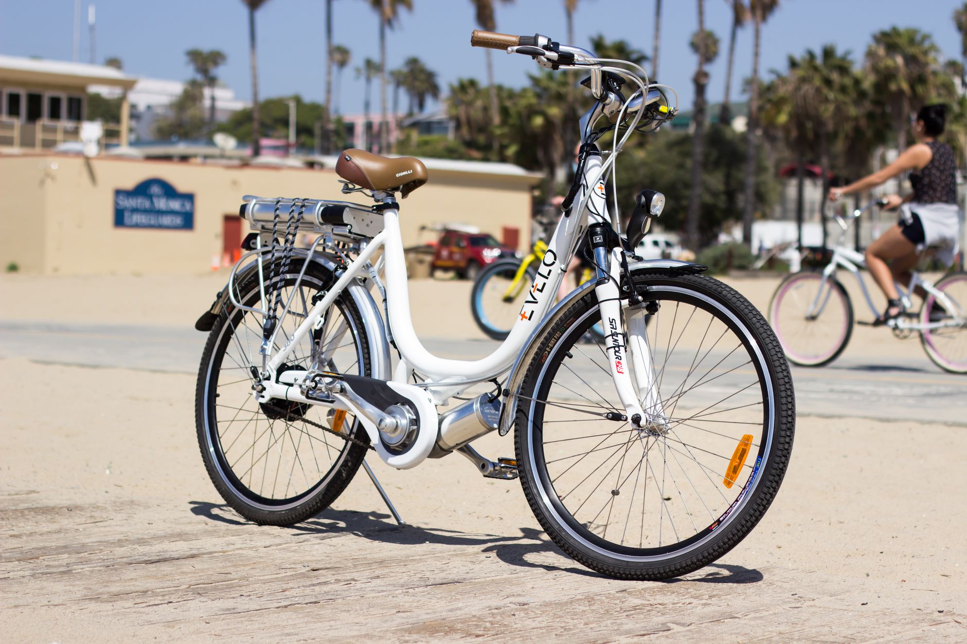 A white electric bicycle parked on Santa Monica's sunny beach path, showcasing leisure and travel.